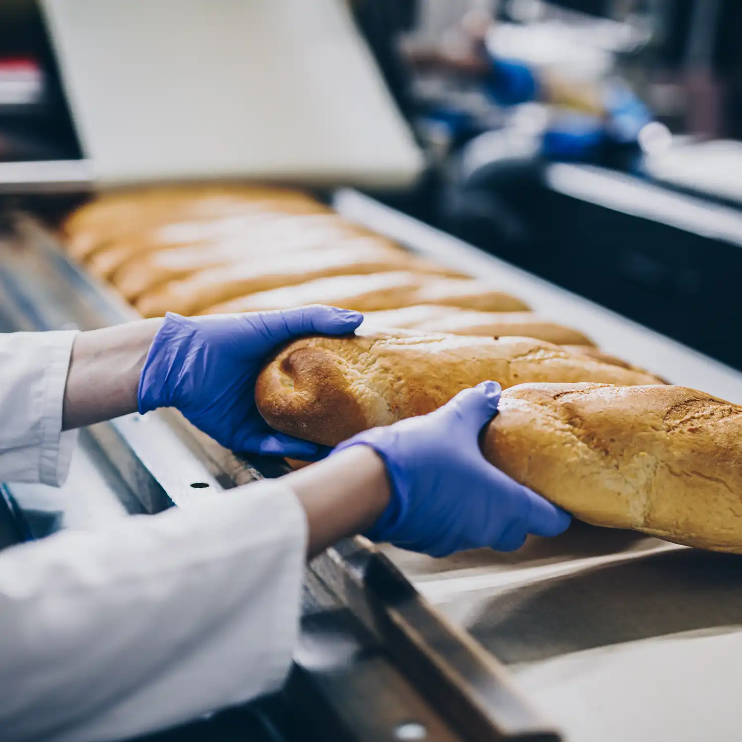 Bäckerin, die an einer Brotproduktionslinie arbeitet.