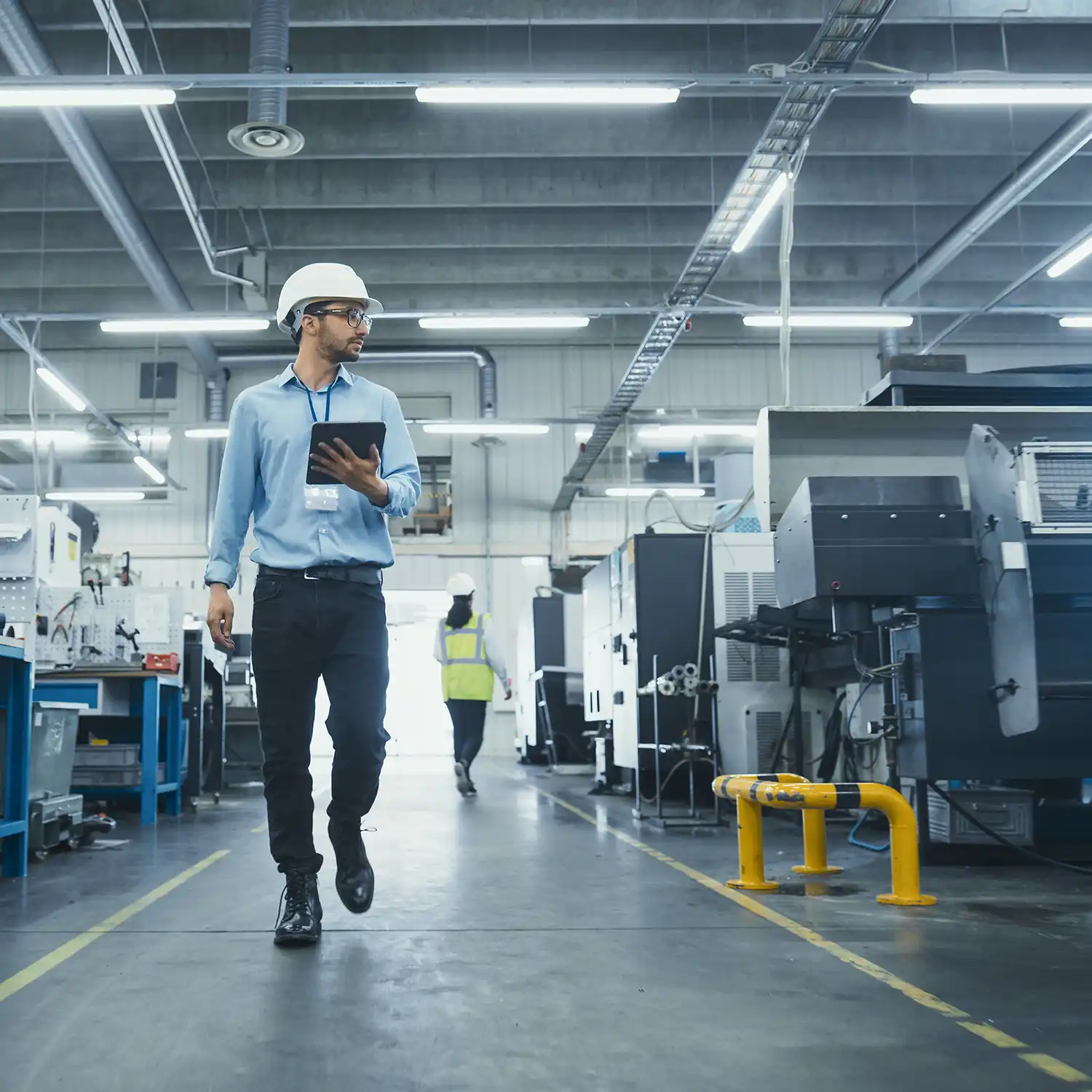 Technischer Leiter in einer Fabrik zur Herstellung von Metallkomponenten. Junger Spezialist aus dem Nahen Osten, der durch die Anlage geht und den Fertigungsprozess mit einem Tablet-Computer überwacht.